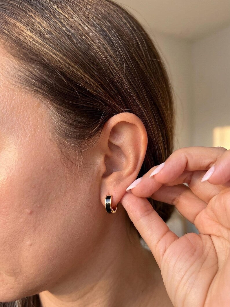 Model wearing black enamel huggie hoop earring