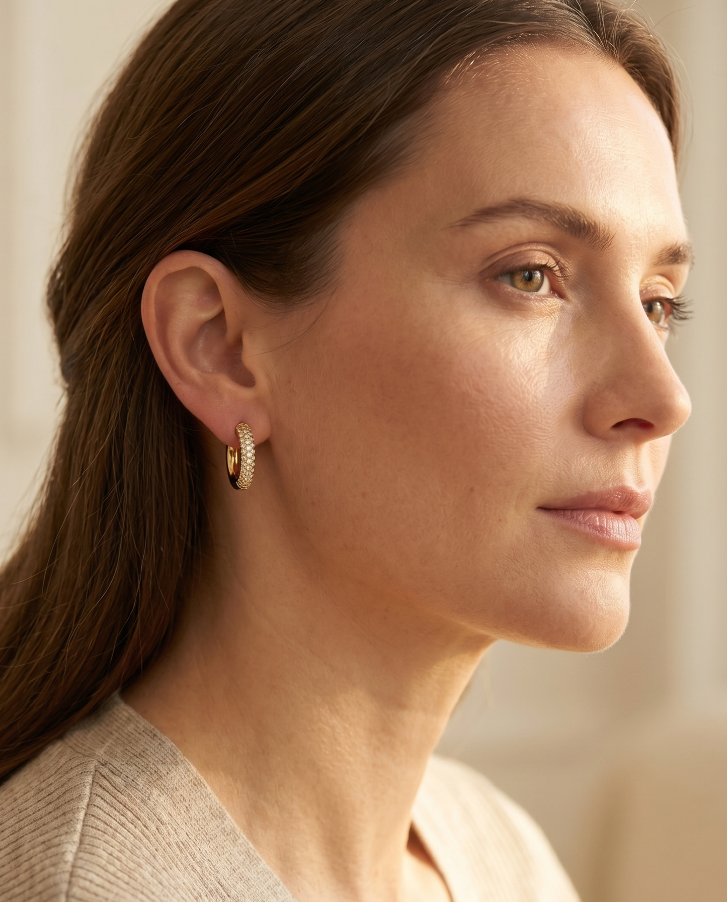 Woman wearing gold hoop earrings with a neutral background