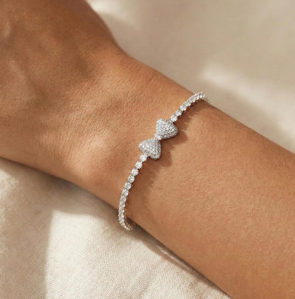 White gold crystal bow bracelet with pavé bow centerpiece and tennis style crystal chain. Elegant feminine bracelet featuring sparkling crystals and white gold filled finish. Lightweight and comfortable jewelry designed for everyday wear or special occasions. Beautiful gift bracelet perfect for Valentine’s Day, anniversaries, birthdays, bridesmaids, or romantic gifts for women.