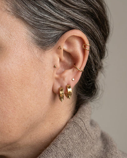 Close-up of 8mm gold spiky huggie hoop earring showing size and spike texture