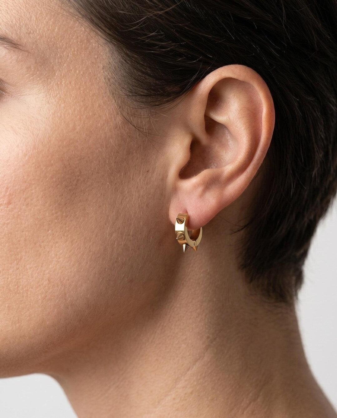 Gold spiky huggie hoop earrings flat lay — tiny stainless steel hoops with spike detail