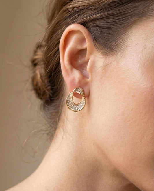 Crystal pavé ribbon stud earrings lifestyle shot — gold finish, worn on ear