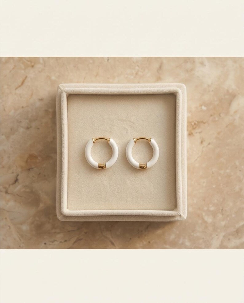 White enamel huggie hoop earrings product flat lay