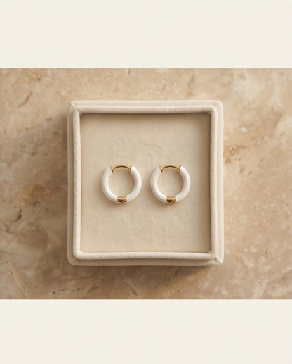 White enamel huggie hoop earrings product flat lay