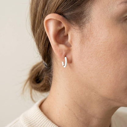 White enamel huggie hoops close up