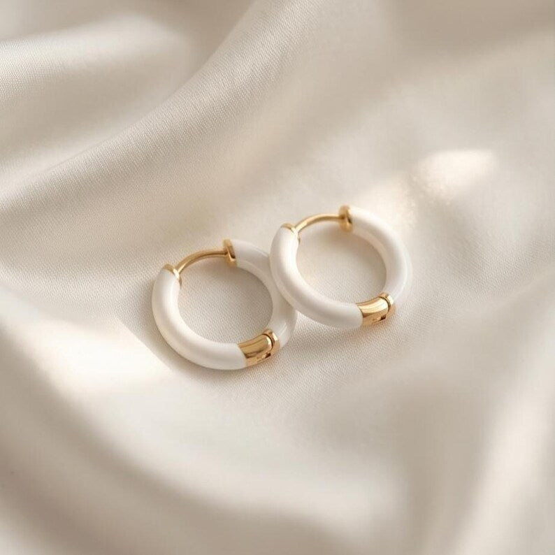 White enamel huggie hoop earrings worn on ear