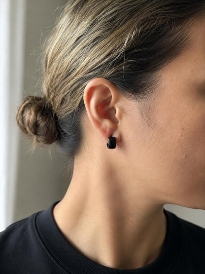 Black stainless steel huggie hoop earrings worn