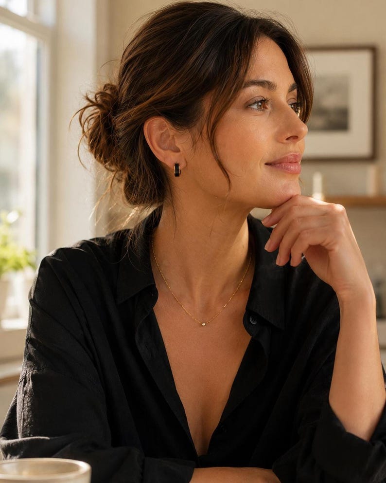Model wearing black enamel huggie hoop earring with necklace