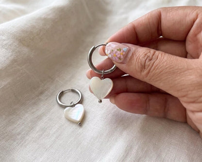 Hand holding Mother of Pearl heart earring
