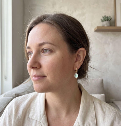 Model wearing teardrop-shaped Mother of Pearl charm earring