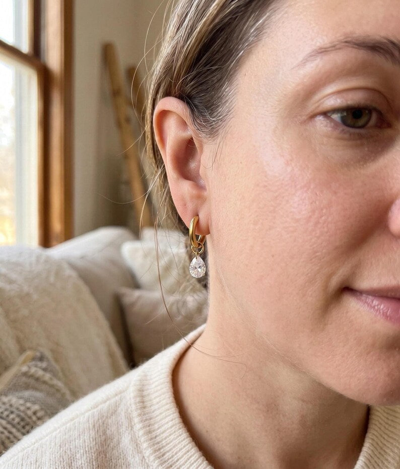 Model wearing gold huggie earring with CZ teardrop charm