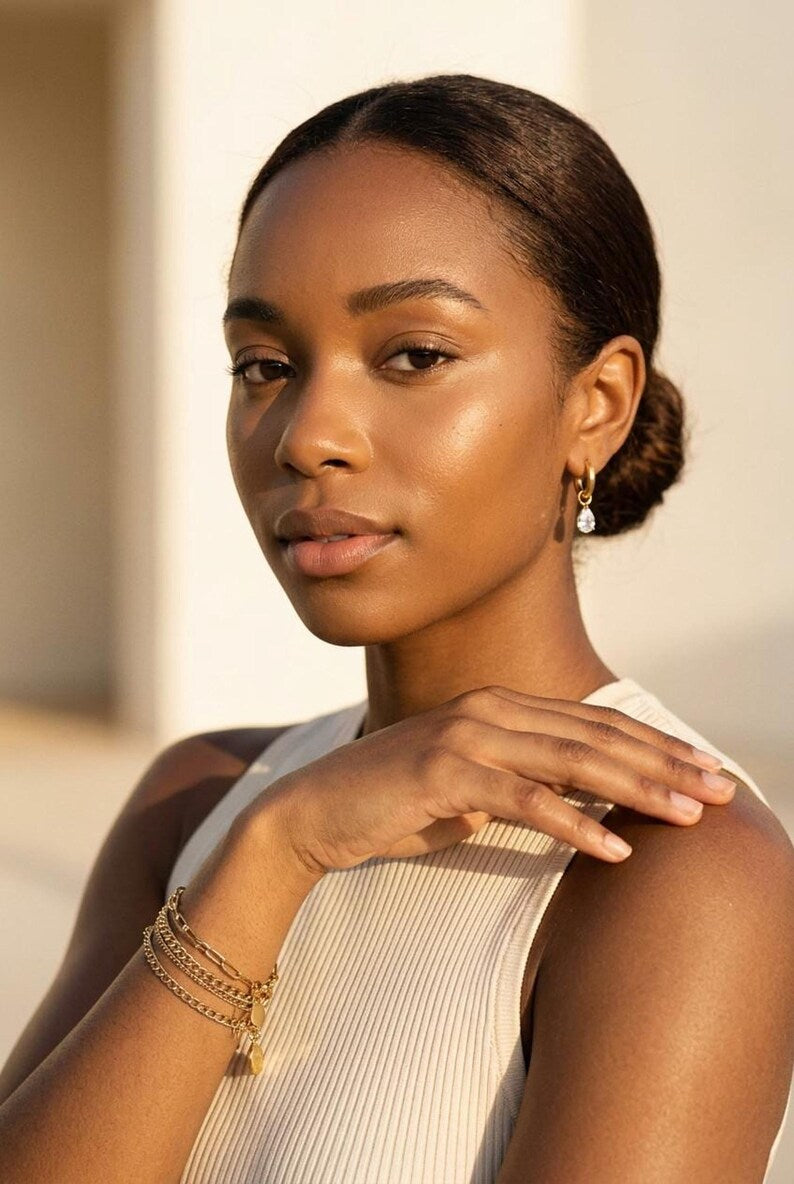 Model wearing gold huggie earring with CZ teardrop
