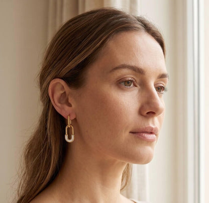 Model wearing gold safety pin huggie hoop earring