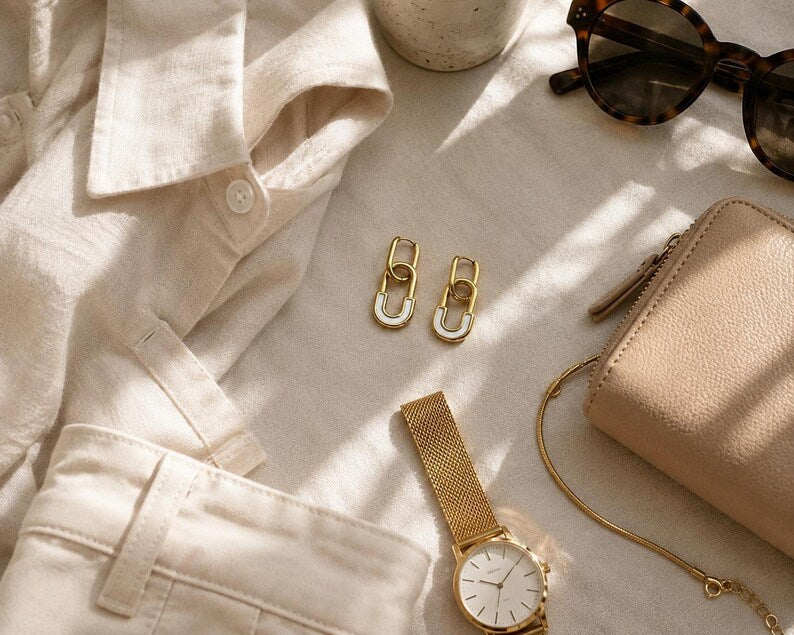 Gold safety pin huggie hoop earrings flat lay with accessories