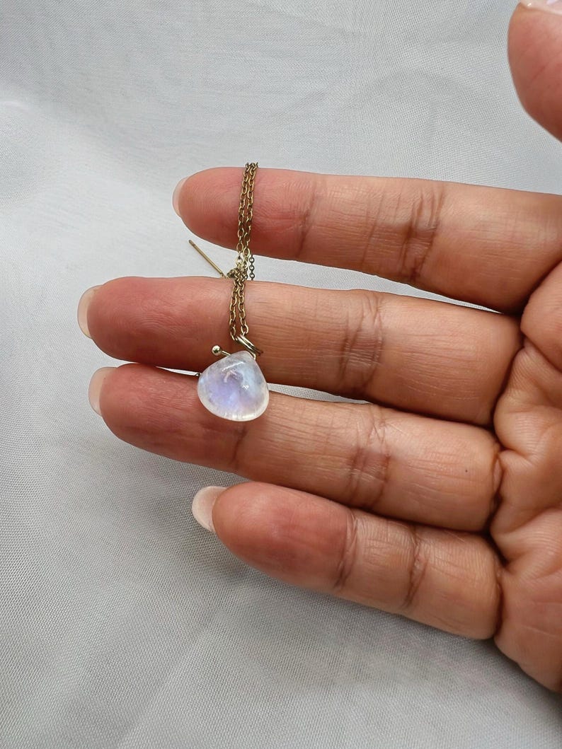 Hand holding gold moonstone necklace