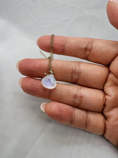 Hand holding gold moonstone necklace