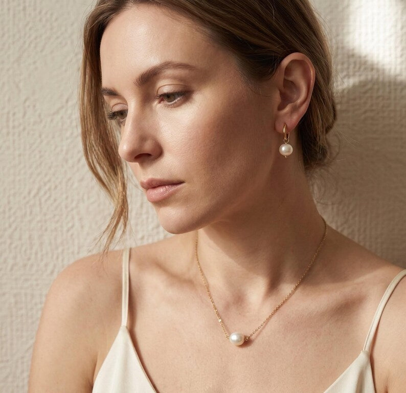Model wearing pearl necklace and drop earrings