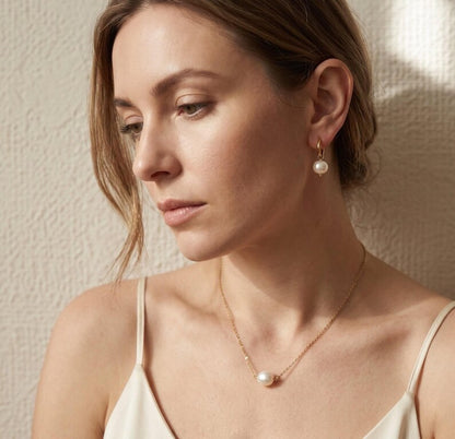 Model wearing pearl necklace and drop earrings
