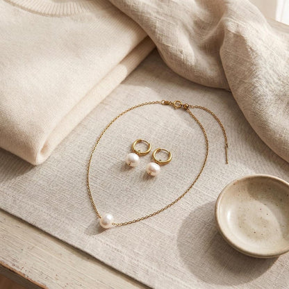 Pearl necklace and earrings set flat lay with sweater