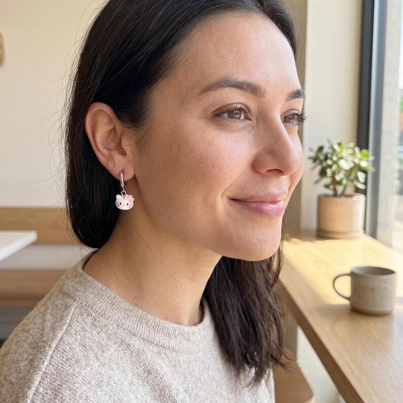 Smiling model wearing kitty charm huggie earring