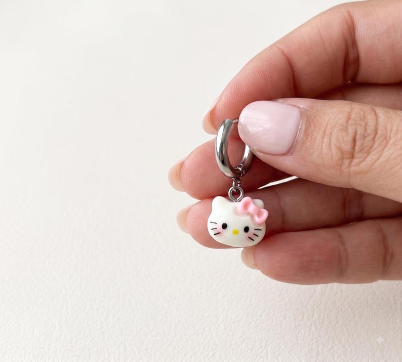 Hand holding kitty charm huggie hoop earring