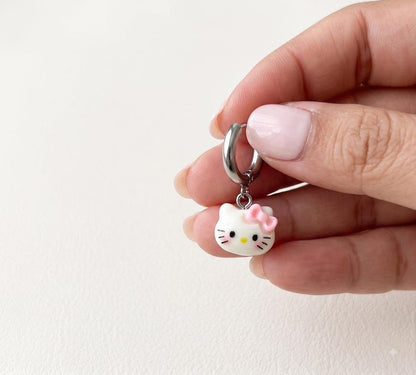 Hand holding kitty charm huggie hoop earring