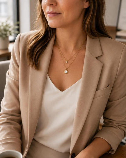 Model wearing layered gold CZ necklace with blazer