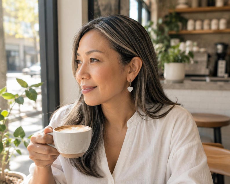 Model wearing Mother of Pearl heart earring at cafe