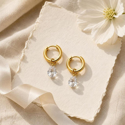 Gold huggie earrings with CZ teardrop on textured paper