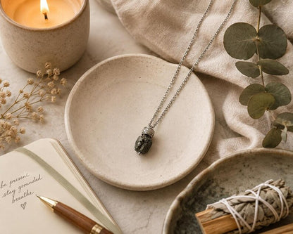 Raw hematite pendant necklace with candle and notebook
