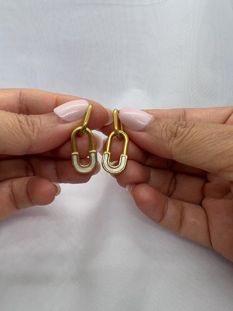 Hands holding gold safety pin huggie hoop earrings