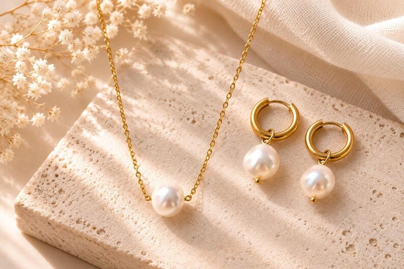Pearl necklace and earrings on stone slab with flowers