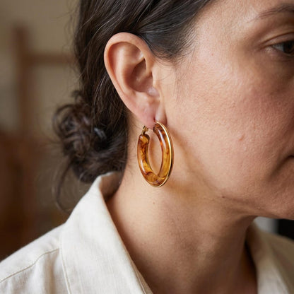 Close-up profile of tortoiseshell resin hoop earring being worn