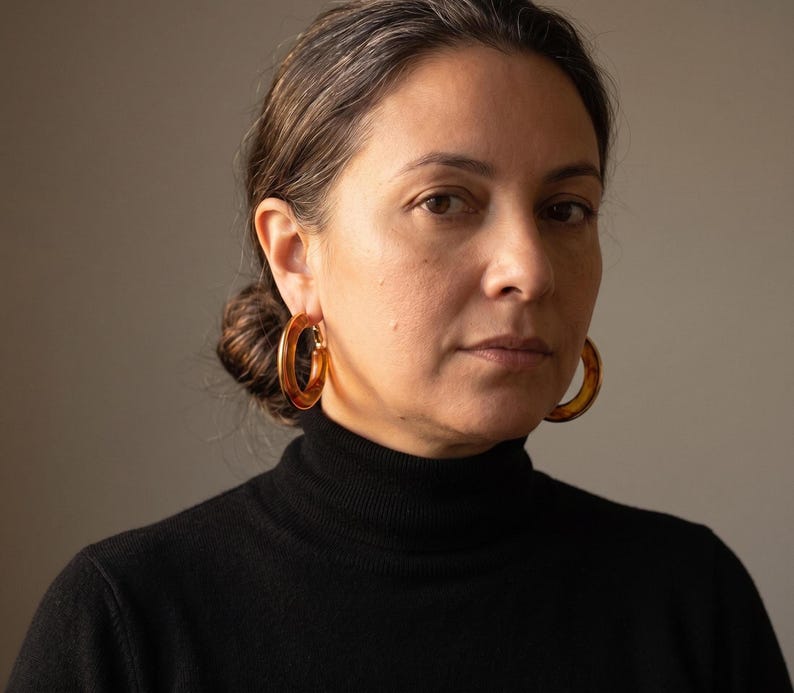 Front-facing portrait wearing tortoiseshell hoop earrings
