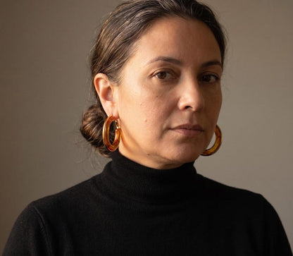 Front-facing portrait wearing tortoiseshell hoop earrings