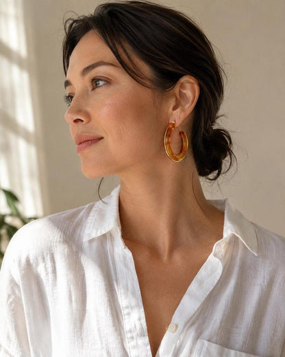 Close-up of model wearing gold-rimmed tortoiseshell resin hoop earrings