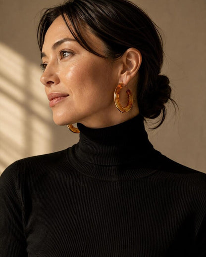Portrait wearing amber resin hoop earrings with gold edges