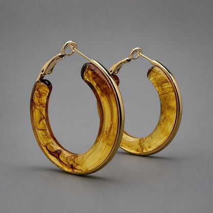 Studio shot of gold-rimmed tortoiseshell resin hoop earrings