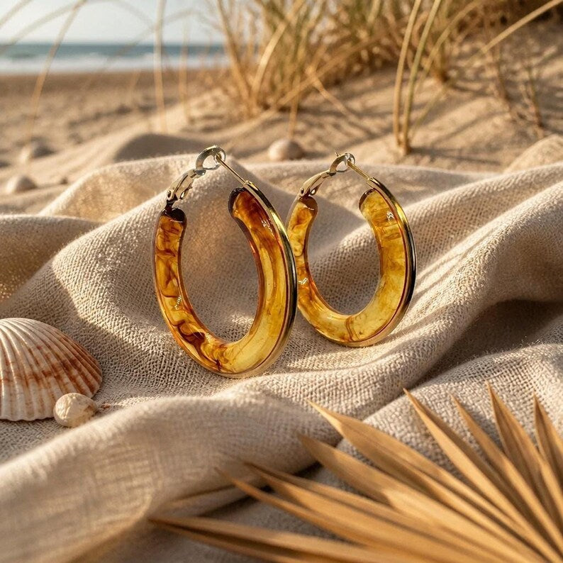 Hoop earrings resting on sand-colored fabric at the beach