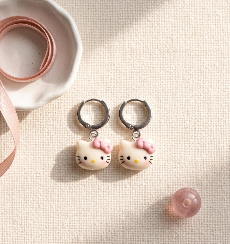 Overhead view of kitty charm huggie hoop earrings