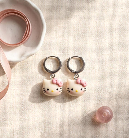 Overhead view of kitty charm huggie hoop earrings
