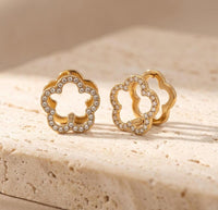 CZ pave floral huggie hoop earrings on textured stone surface