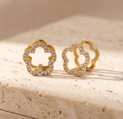 CZ pave floral huggie hoop earrings on textured stone surface