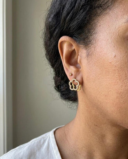 Gold flower huggie earring paired with small gold stud