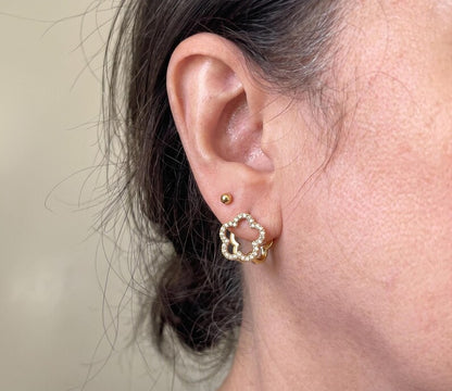Detailed close-up of gold floral hoop earring with CZ stones