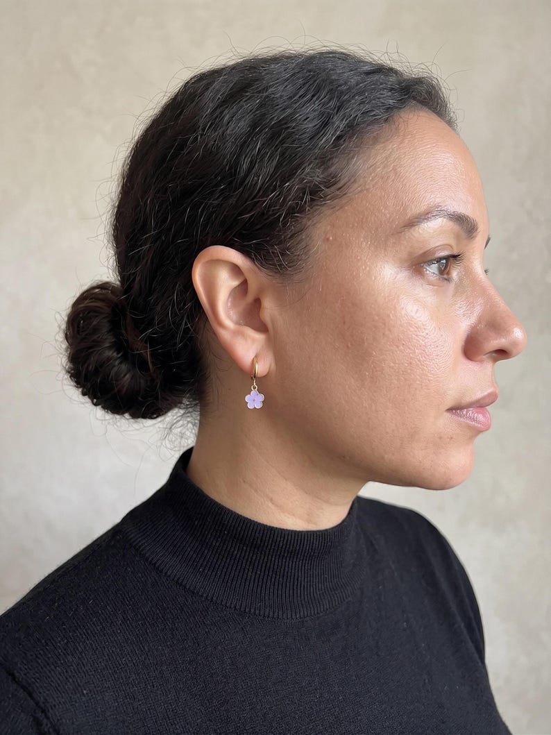 Profile portrait wearing gold hoop with purple flower dangle