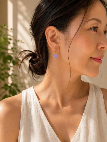 Person wearing gold flower huggie earring and white top