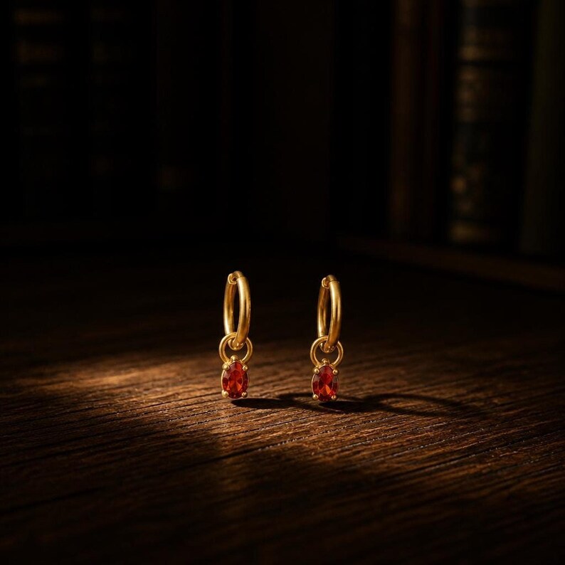 CZ huggie hoop earrings on wood surface with spotlight