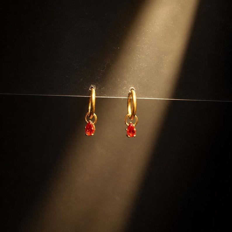 CZ huggie hoop earrings against dark backdrop