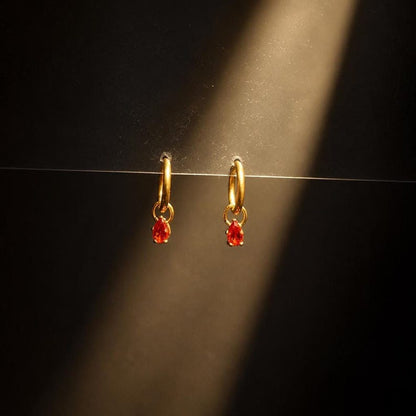 CZ huggie hoop earrings against dark backdrop